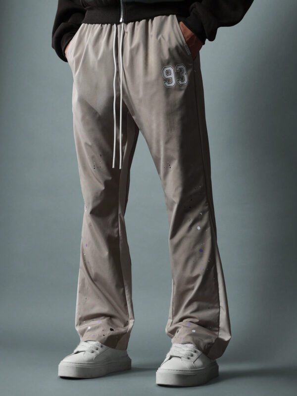 SUMWON Pantalon en nylon avec ajustement évasé, panneau latéral bicolore, imprimé graphique avec éclaboussures de peinture et numéros, avec cordons de serrage – Image 2