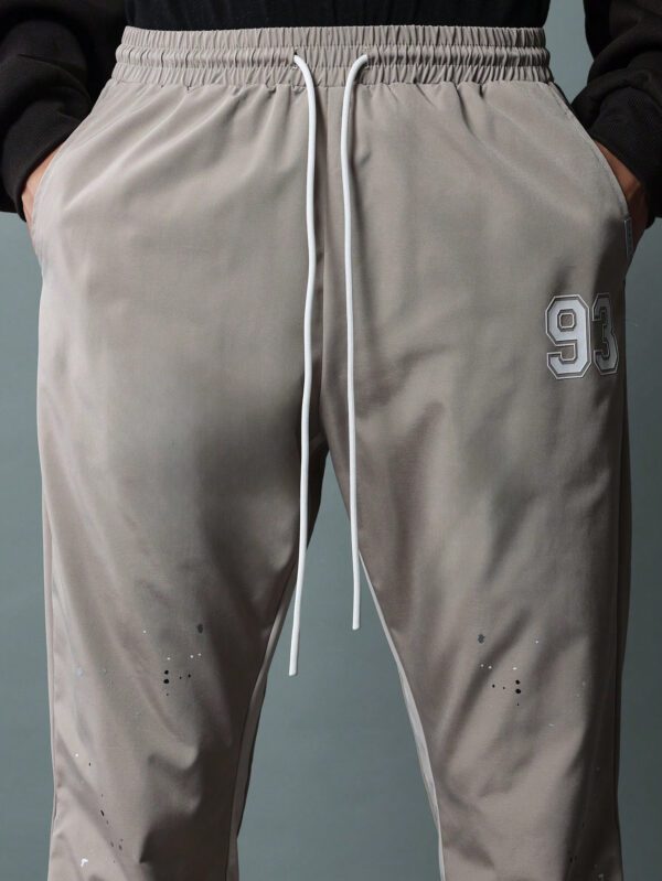 SUMWON Pantalon en nylon avec ajustement évasé, panneau latéral bicolore, imprimé graphique avec éclaboussures de peinture et numéros, avec cordons de serrage – Image 6